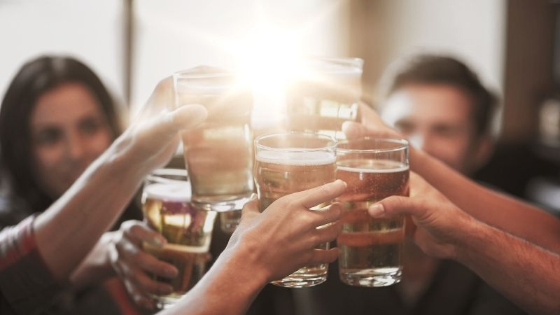 Várias pessoas fazem um brinde com bebidas durante um open bar
