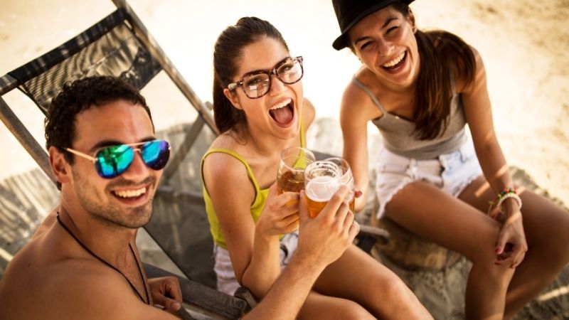 Vários amigos de festa na praia brindando com cerveja